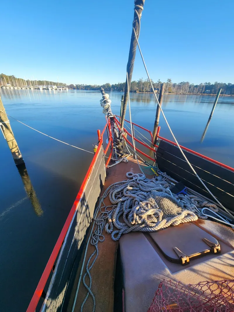 Slide: The Image of 1982 Watkins 27 Pirate Ship on calm water, ropes on deck, clear blue sky. - 6