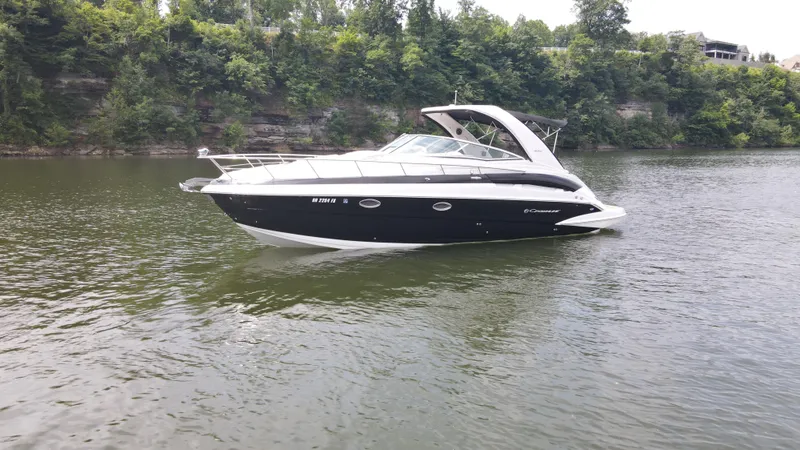 Slide: The Image of 2020 Crownline 330 SY boat cruising on a calm river with lush green trees. - 2