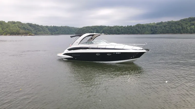 Slide: The Image of 2020 Crownline 330 SY boat on a calm lake with forested shoreline. - 3