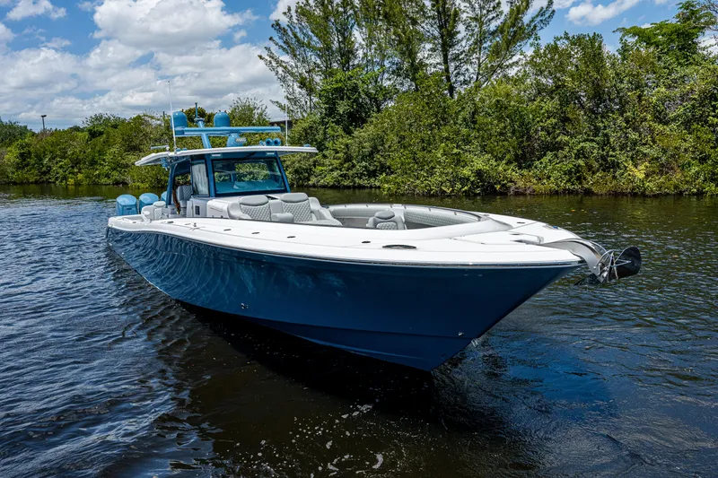 Slide: The Image of 2023 HCB 53 Sueños boat cruising on a sunny day, surrounded by lush greenery. - 37