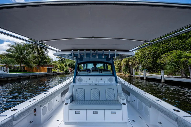 Slide: The Image of 2023 HCB 53 Sueños boat interior with seating, docked by lush greenery. - 9