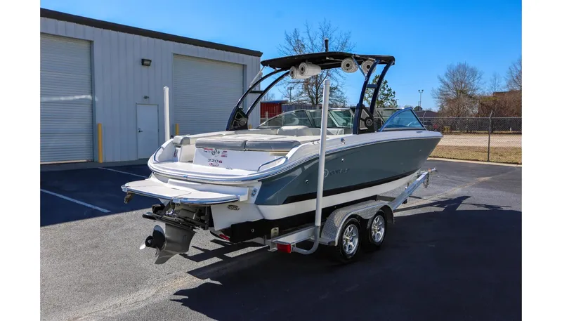 Slide: The Image of 2018 Cobalt 220S boat on trailer, parked outside a warehouse on a sunny day. - 2