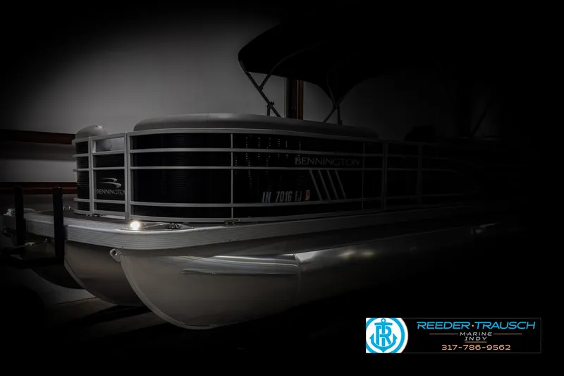 Slide: The Image of 2022 Bennington 23 LSR pontoon boat in a dimly lit showroom. - 4