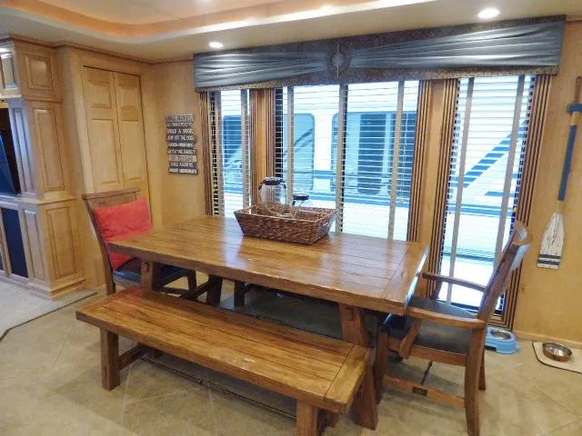 Slide: The Image of 2009 Sumerset 19x105 houseboat interior with wooden dining table and bench seating. - 6