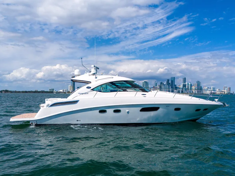 Slide: The Image of 2011 Sea Ray 470 Sundancer yacht cruising on open water with city skyline backdrop. - 1