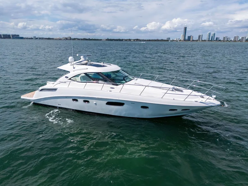Slide: The Image of 2011 Sea Ray 470 Sundancer yacht cruising on open water with city skyline in background. - 15