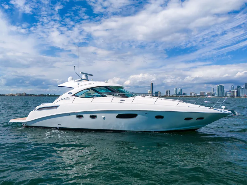 Slide: The Image of 2011 Sea Ray 470 Sundancer yacht cruising on open water with city skyline backdrop. - 3