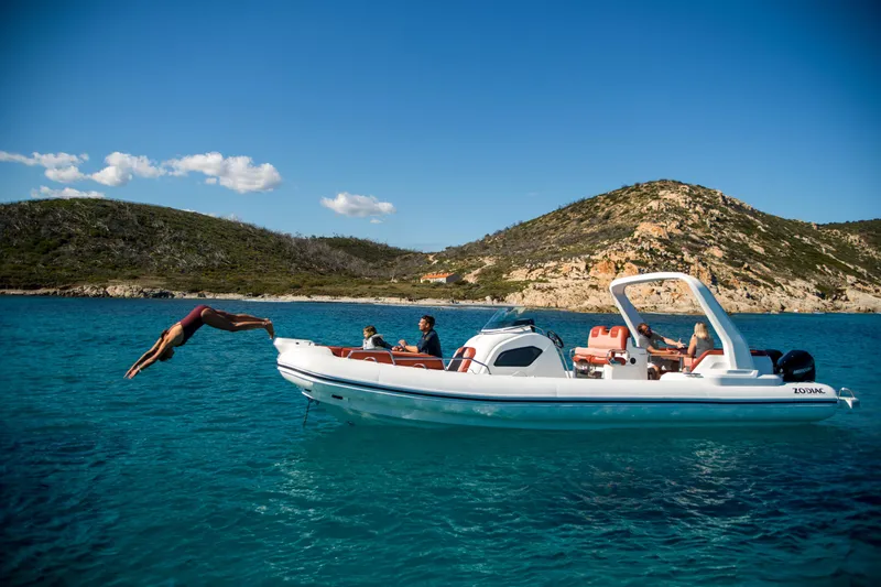 Slide: The Image of 2025 Zodiac Medline 9 boat in clear blue water, person diving, scenic hills in background. - 25