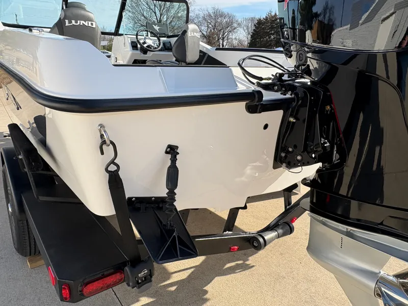 Slide: The Image of 2025 Lund 185 Impact GL boat on trailer, rear view with motor and seating visible. - 11