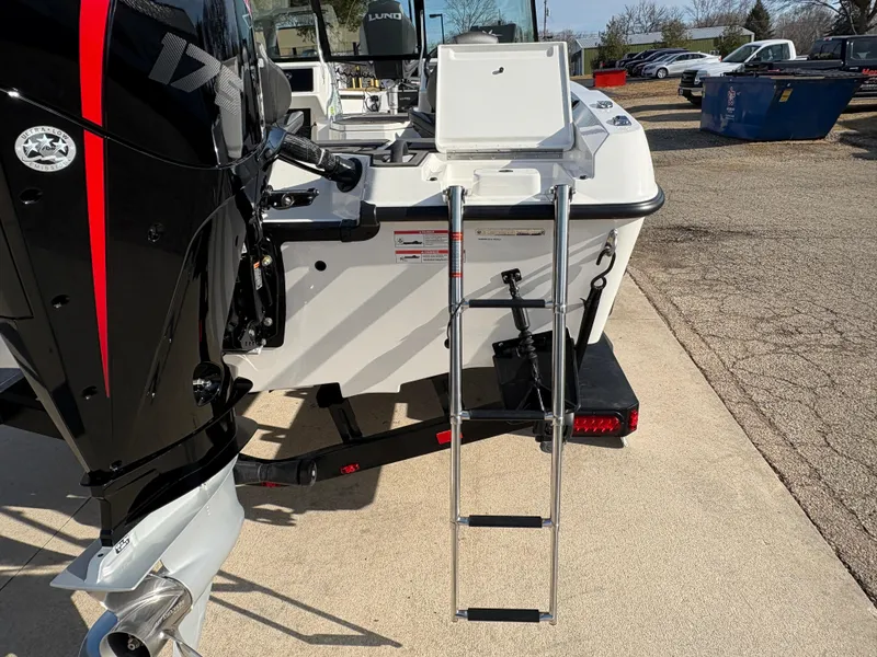 Slide: The Image of 2025 Lund 185 Impact GL boat with ladder and outboard motor, parked on concrete. - 13