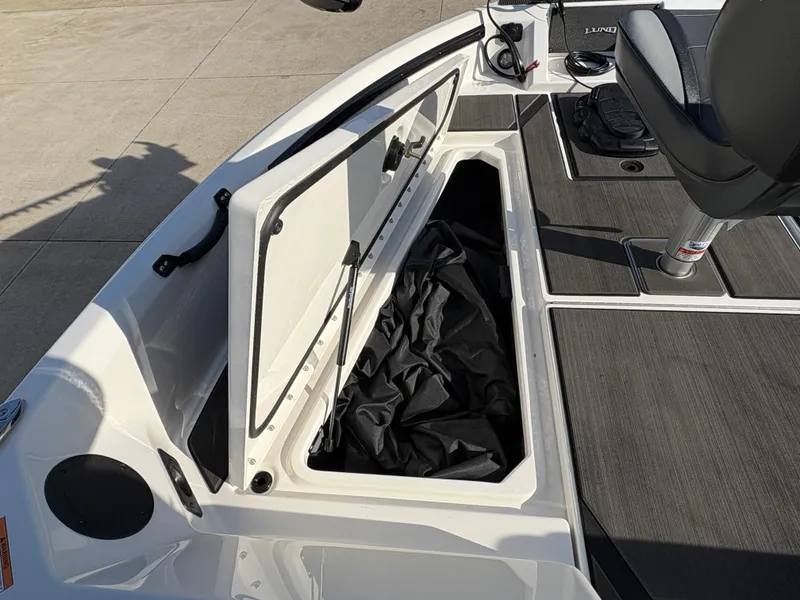 Slide: The Image of 2025 Lund 185 Impact GL boat storage compartment with open lid and seating area. - 15