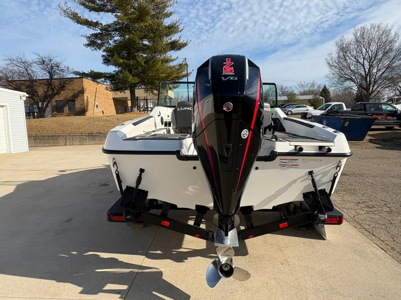 Slide: The Image of 2025 Lund 185 Impact GL boat with powerful outboard motor, parked outdoors. - 2