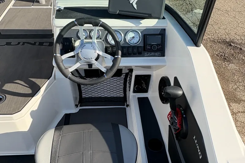 Slide: The Image of 2025 Lund 185 Impact GL boat cockpit with steering wheel and dashboard controls. - 27