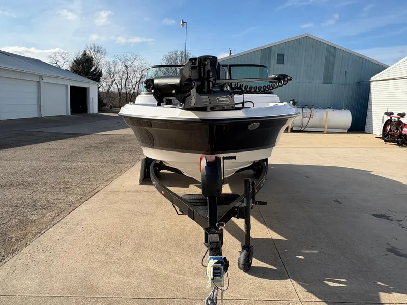 Slide: The Image of 2025 Lund 185 Impact GL boat on trailer, parked outdoors near garages. - 6