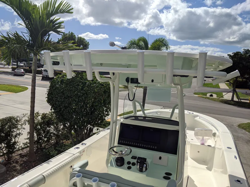 Slide: The Image of Sea Born LX26 boat console with T-top, parked outdoors under a partly cloudy sky. - 6