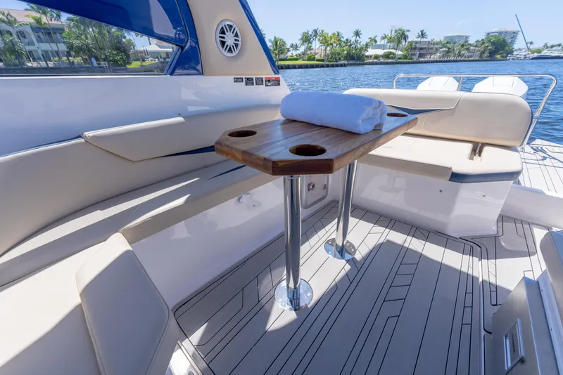 Slide: The Image of 2025 Hanover 305 Outboard boat interior with wooden table and seating, overlooking a scenic waterway. - 11