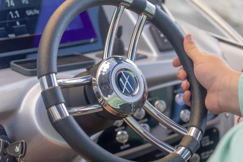 Slide: The Image of Steering wheel of a 2025 Hanover 305 Outboard boat, with a hand gripping it. - 17