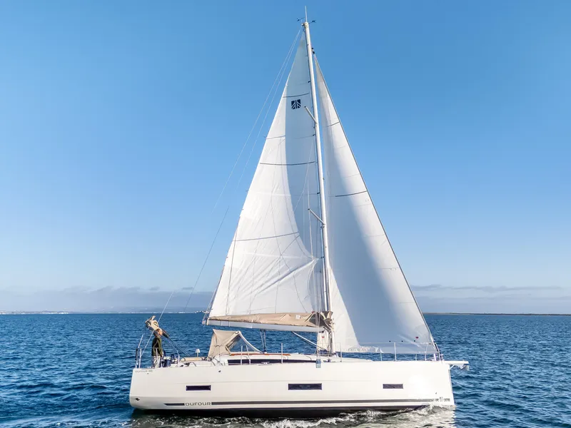 The Image of 2023 Dufour 390 sailboat cruising on open water under clear blue skies. - 0