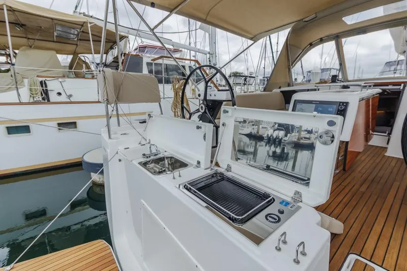 Slide: The Image of 2023 Dufour 390 yacht cockpit with grill and steering wheel, docked at marina. - 12