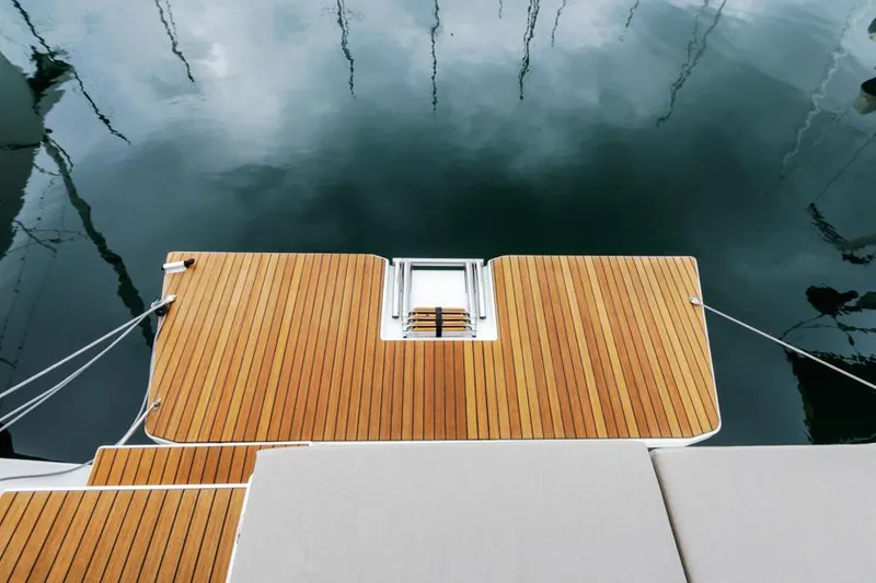 Slide: The Image of Dufour 390 yacht's teak swim platform, 2023 model, reflecting on calm water. - 13