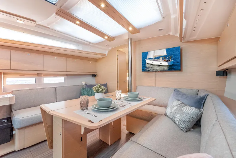 Slide: The Image of Interior of 2023 Dufour 390 yacht, featuring modern dining area with light wood and gray upholstery. - 17