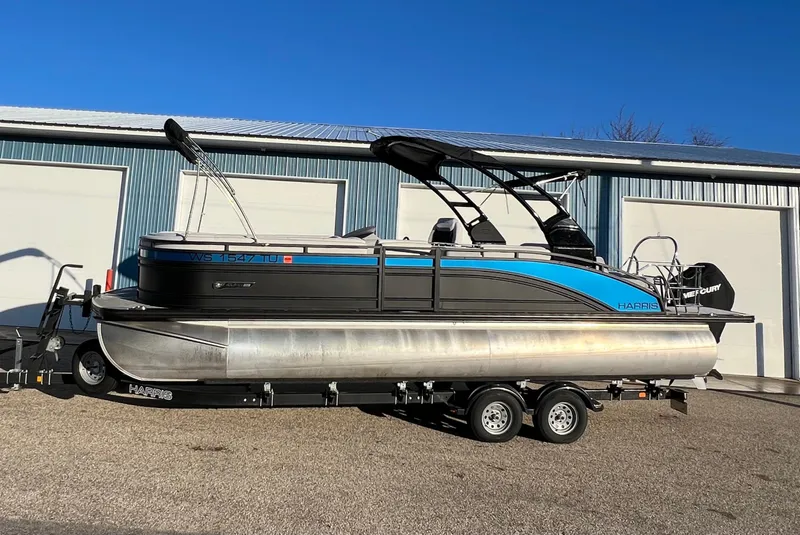Slide: The Image of 2023 Harris Solstice 250 pontoon boat on trailer, parked outside a garage. - 16