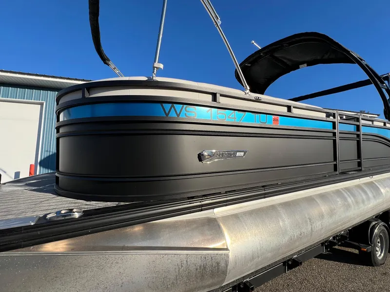 Slide: The Image of 2023 Harris Solstice 250 pontoon boat on trailer, blue and black design, sunny day. - 17