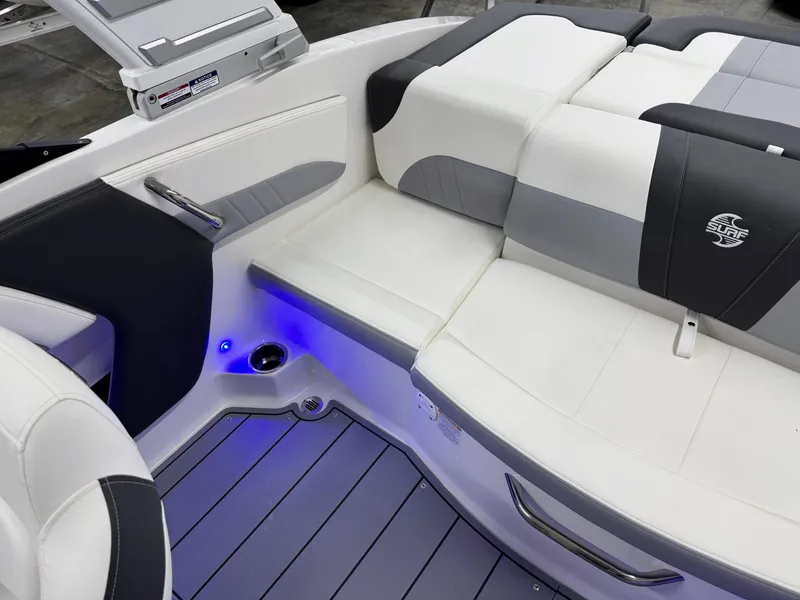 Slide: The Image of 2025 Chaparral 21 Surf boat interior with white and gray seating, blue LED lighting. - 22