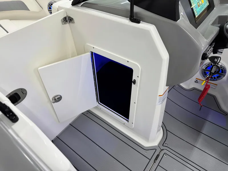 Slide: The Image of 2025 Chaparral 21 Surf boat interior with open storage compartment and modern dashboard. - 31