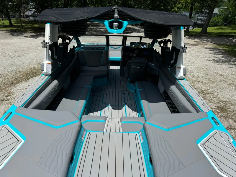 Slide: The Image of 2025 Nautique G25 boat interior with gray and blue seating, open canopy, and modern design. - 13