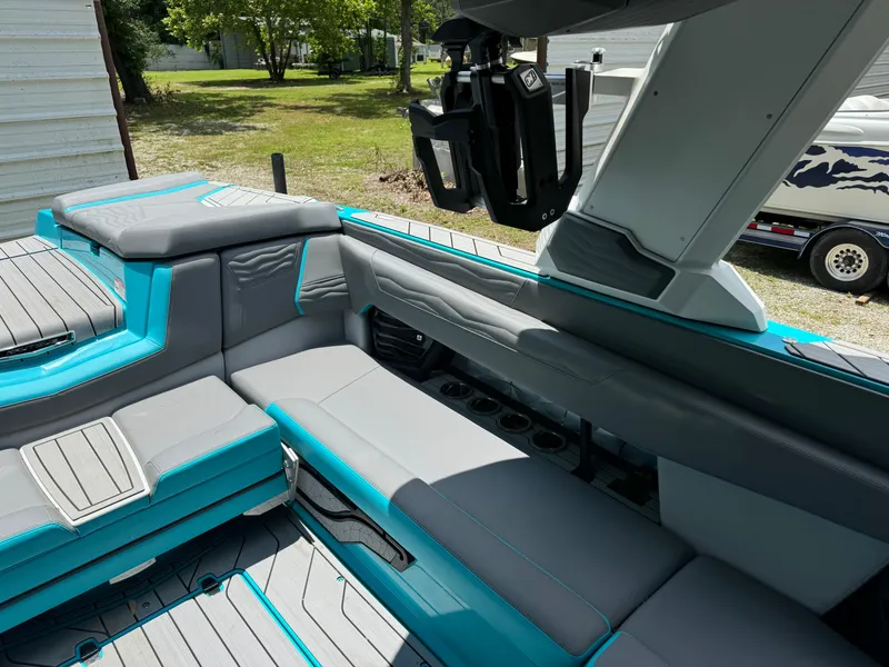 Slide: The Image of 2025 Nautique G25 boat interior with gray and teal seating, cup holders, and wakeboard rack. - 18