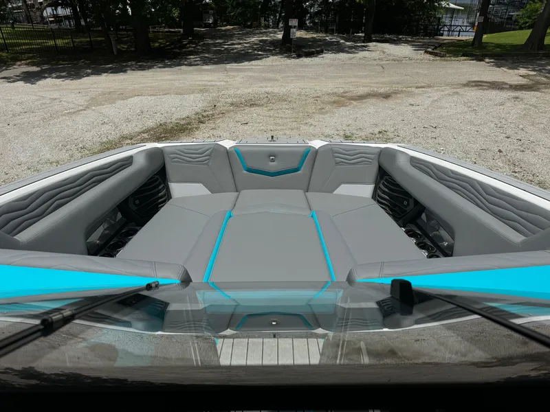 Slide: The Image of 2025 Nautique G25 boat interior with gray and teal seating, parked on gravel. - 19