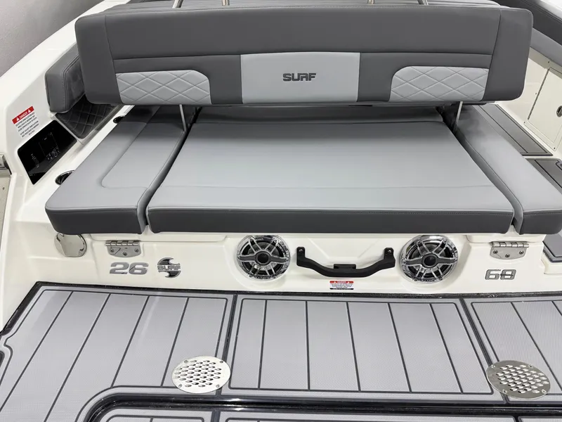 Slide: The Image of 2025 Chaparral 26 Surf boat with gray seating and deck, featuring speakers and storage. - 11