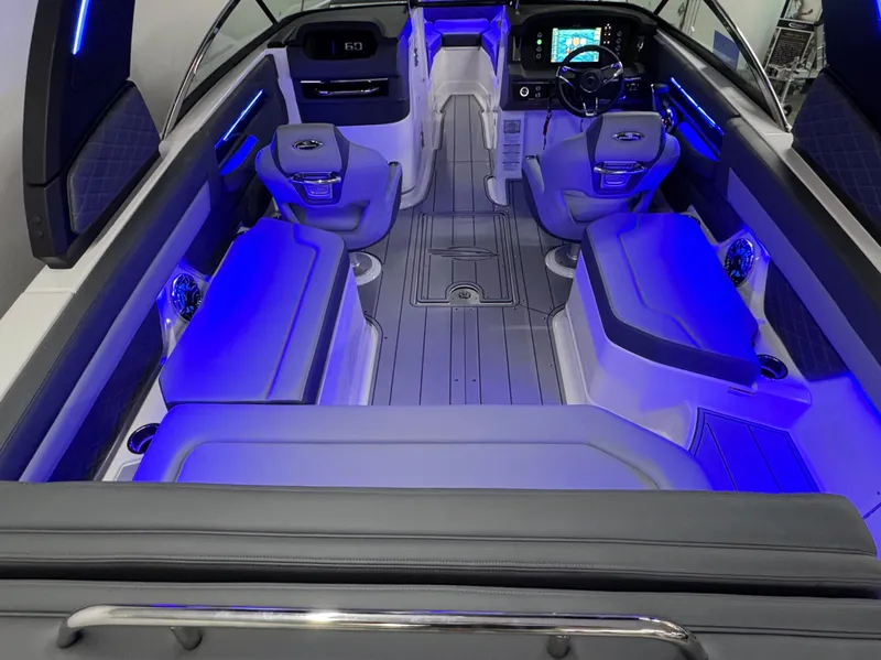Slide: The Image of 2025 Chaparral 26 Surf boat interior with modern seating and ambient blue lighting. - 16