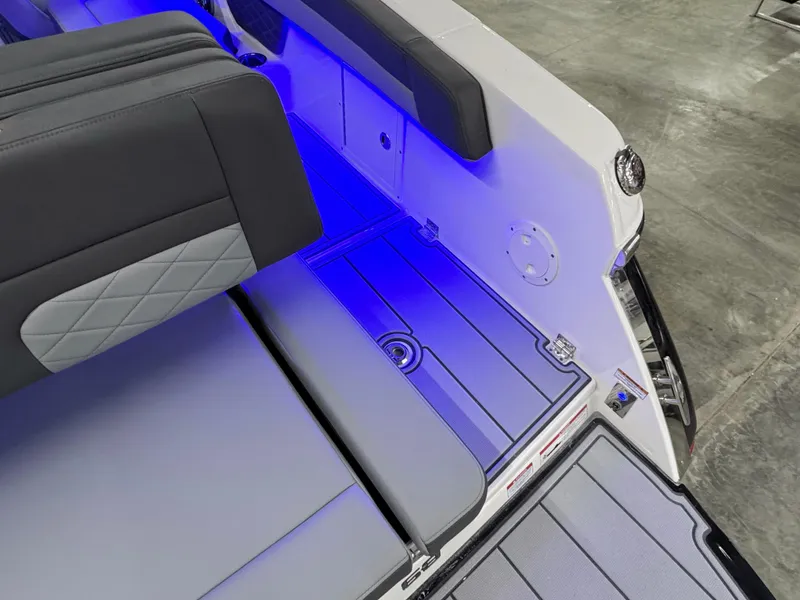 Slide: The Image of 2025 Chaparral 26 Surf boat interior with blue LED lighting and cushioned seating. - 17