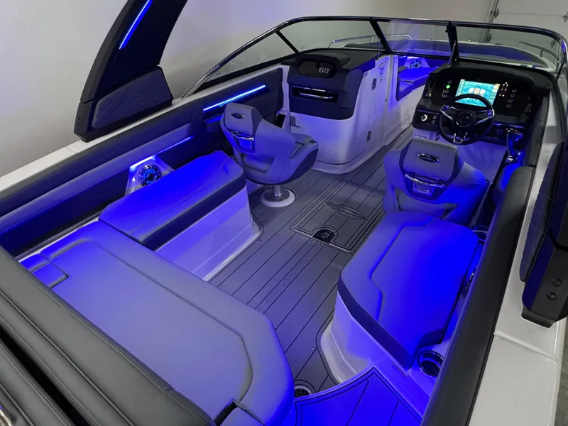 Slide: The Image of 2025 Chaparral 26 Surf boat interior with blue LED lighting and modern seating. - 21