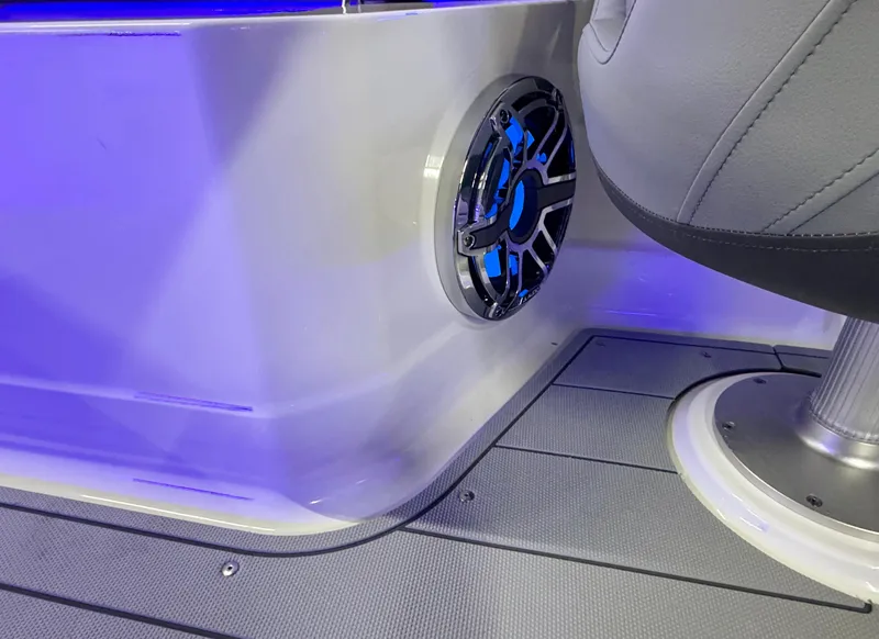 Slide: The Image of 2025 Chaparral 26 Surf boat interior with speaker and seating, illuminated by blue lighting. - 25
