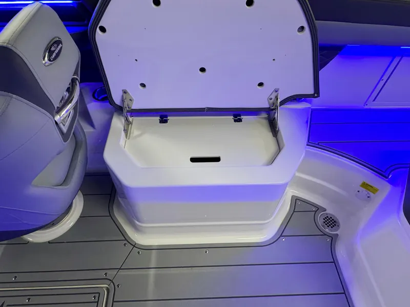 Slide: The Image of 2025 Chaparral 26 Surf boat interior with open storage compartment and blue LED lighting. - 28