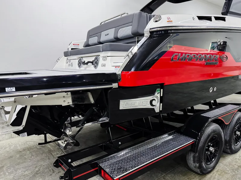 Slide: The Image of 2025 Chaparral 26 Surf boat, red and black design, on a trailer in a showroom. - 4