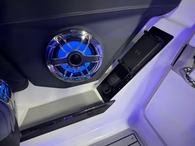 Slide: The Image of 2025 Chaparral 26 Surf boat interior with illuminated speaker and storage compartment. - 51