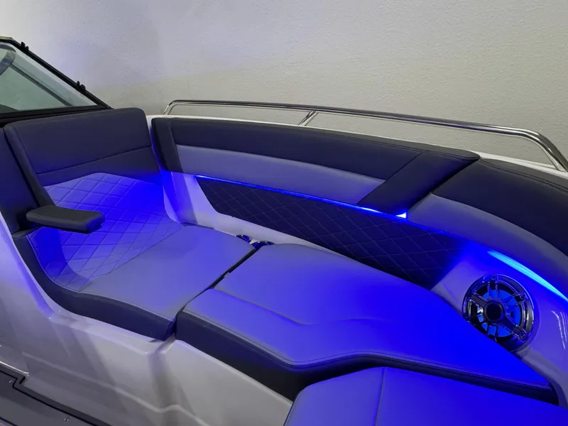 Slide: The Image of 2025 Chaparral 26 Surf boat interior with blue LED lighting and cushioned seating. - 59