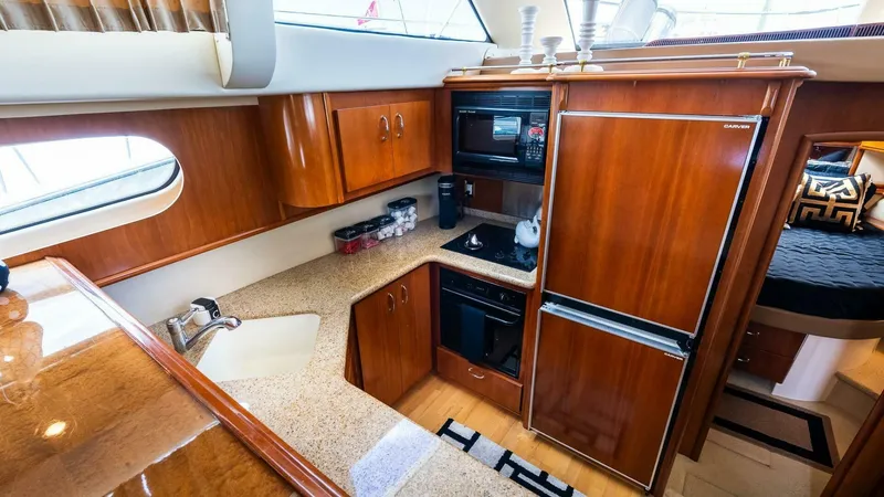 Slide: The Image of 2004 Carver 466 Motor Yacht kitchen with wood cabinetry, appliances, and countertop. - 18