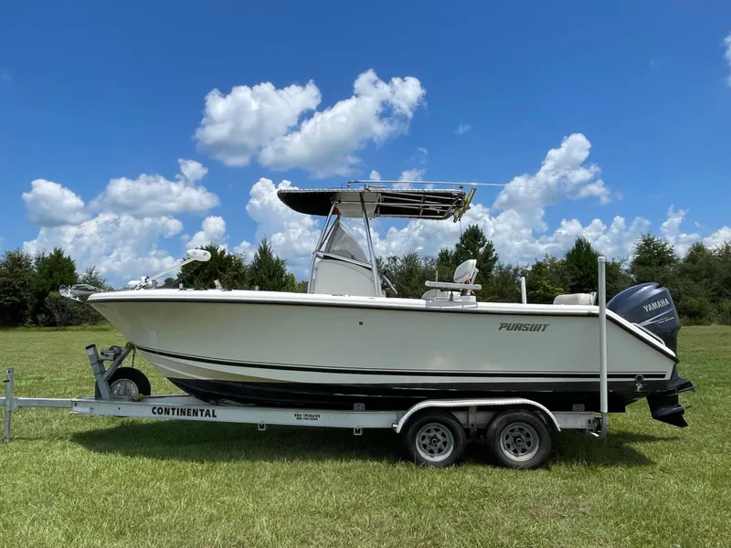 Slide: The Image of 2008 Pursuit 230 Center Console boat on trailer, parked on grassy field under blue sky. - 0