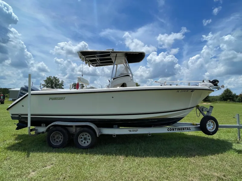 Slide: The Image of 2008 Pursuit 230 Center Console boat on trailer, parked on grassy field under cloudy sky. - 6
