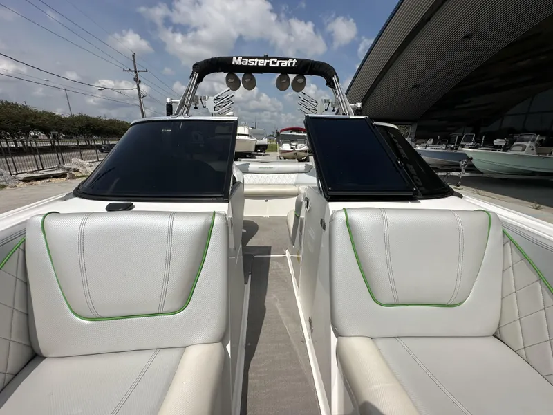 Slide: The Image of 2014 MasterCraft X2 boat interior with white seating and green accents, docked under a blue sky. - 18