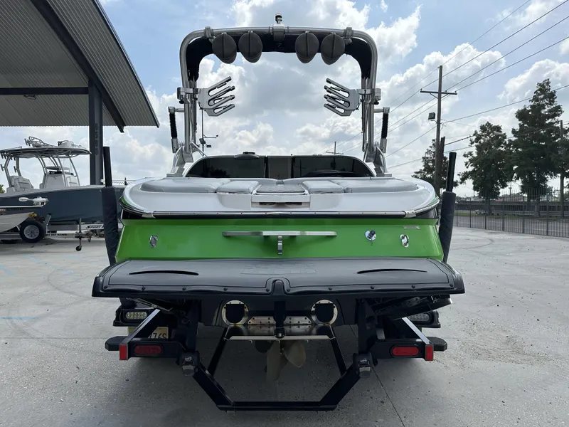 Slide: The Image of 2014 MasterCraft X2 boat, green and white, rear view in a marina setting. - 3