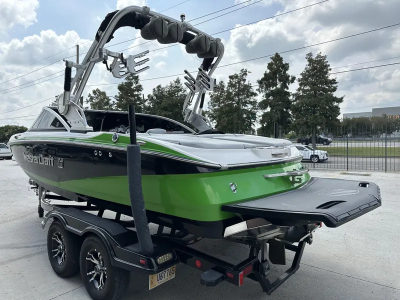 Slide: The Image of 2014 MasterCraft X2 boat on trailer, green and black design, parked outdoors. - 4