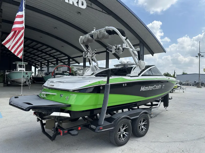 Slide: The Image of 2014 MasterCraft X2 boat in green and black, parked under a large canopy. - 5