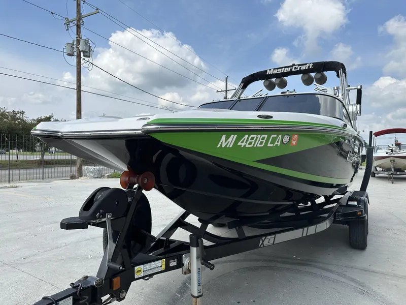 Slide: The Image of 2014 MasterCraft X2 boat on trailer, green and black design, parked outdoors. - 6