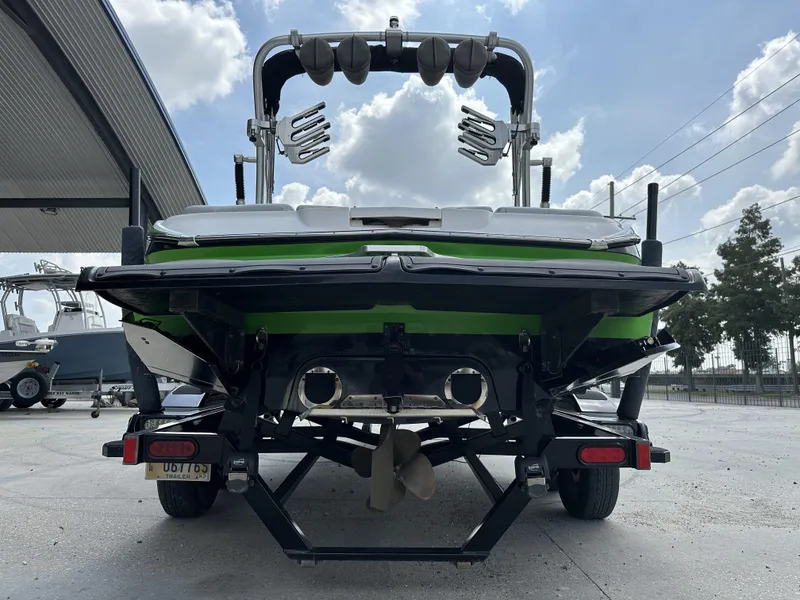 Slide: The Image of 2014 MasterCraft X2 boat rear view with green accents, parked on a trailer. - 8